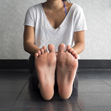 Woman sitting sitting on the ground showing the bottom of her feet